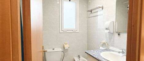 Un baño pequeño con inodoro, bidé y lavabo con espejo.