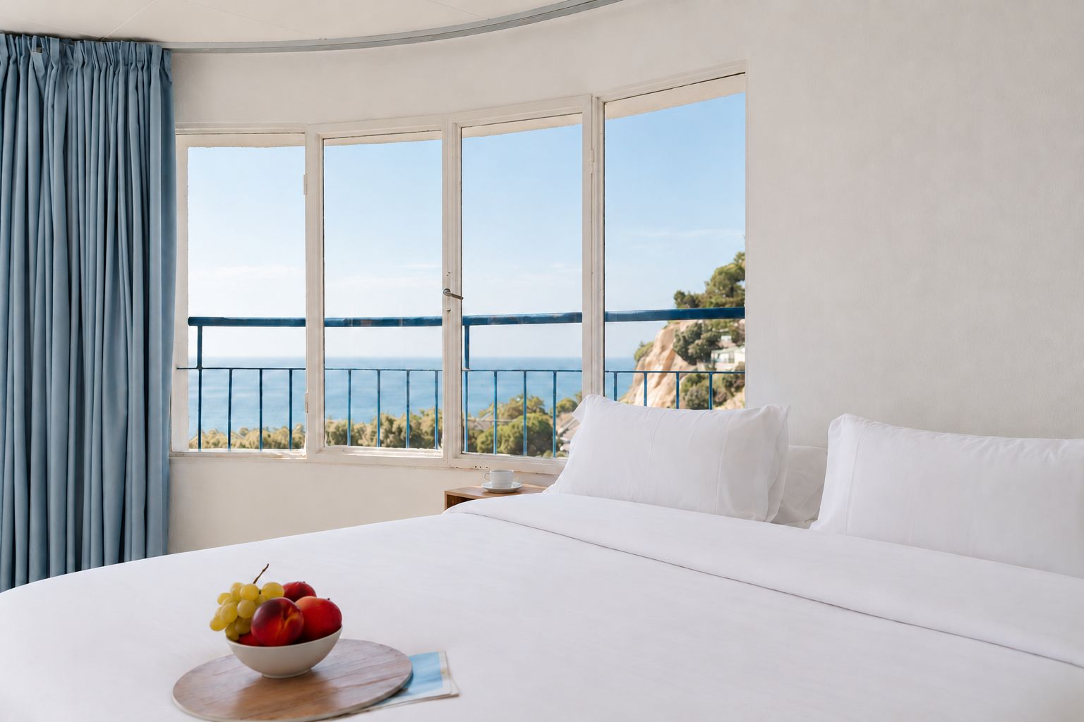 Un cuarto de hotel con una cama grande, un frutero y vista al mar.