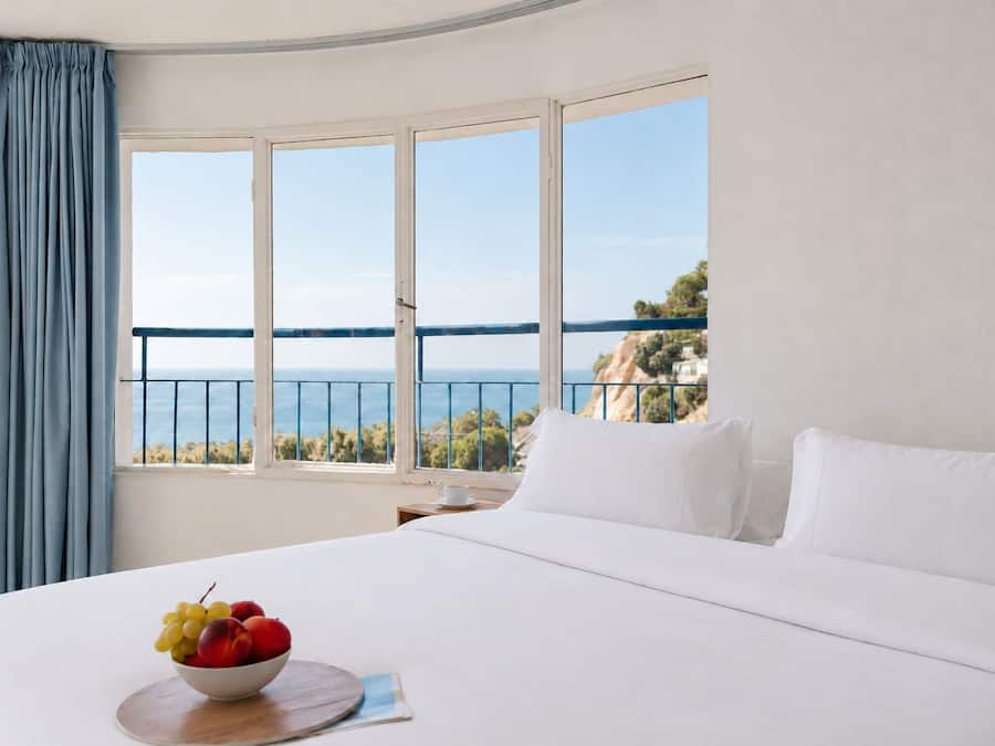 Un cuarto de hotel con una cama grande, un frutero y vista al mar.