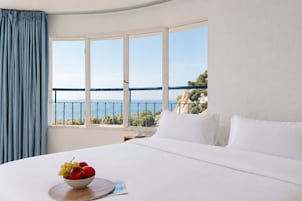 Un cuarto de hotel con una cama grande, un frutero y vista al mar.