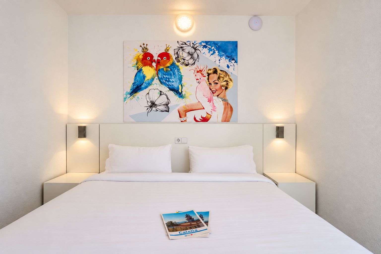 A hotel room with a large bed, two bedside lamps, and a painting on the wall.