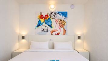 A hotel room with a large bed, two bedside lamps, and a painting on the wall.