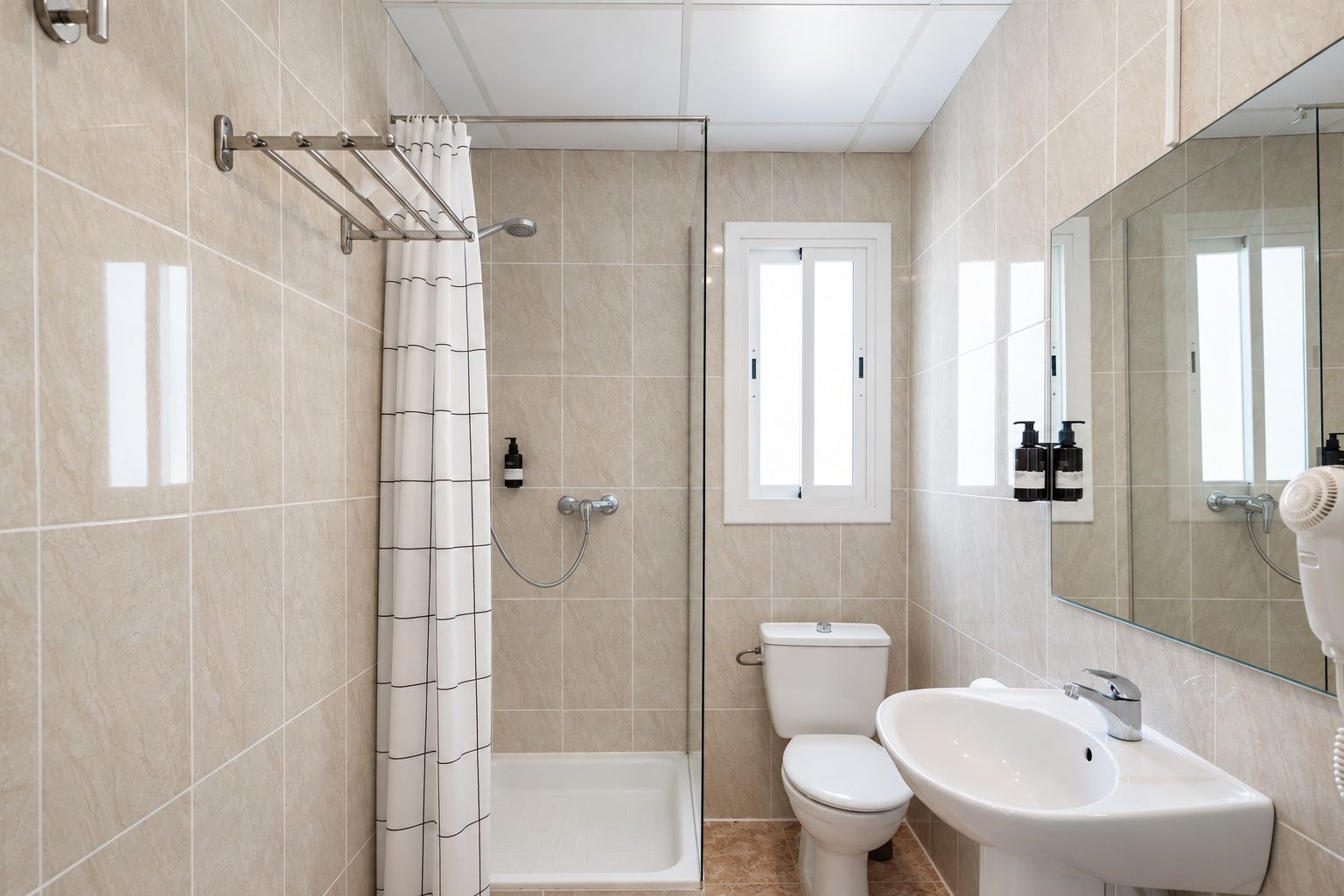 A bathroom with a shower, toilet, and sink, featuring tiled walls and a glass shower enclosure.