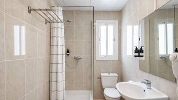 A bathroom with a shower, toilet, and sink, featuring tiled walls and a glass shower enclosure.