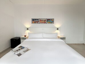 A hotel room with a bed, two bedside tables, a lamp, a small black cabinet, and three framed pictures on the wall. - Las Vegas Hotel (Calella)