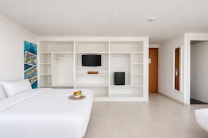 A hotel room with a bed, a TV on a stand, a refrigerator, and a wall-mounted shelf. - Hotel Las Vegas by Olala! - Self check in Hotel (Calella)