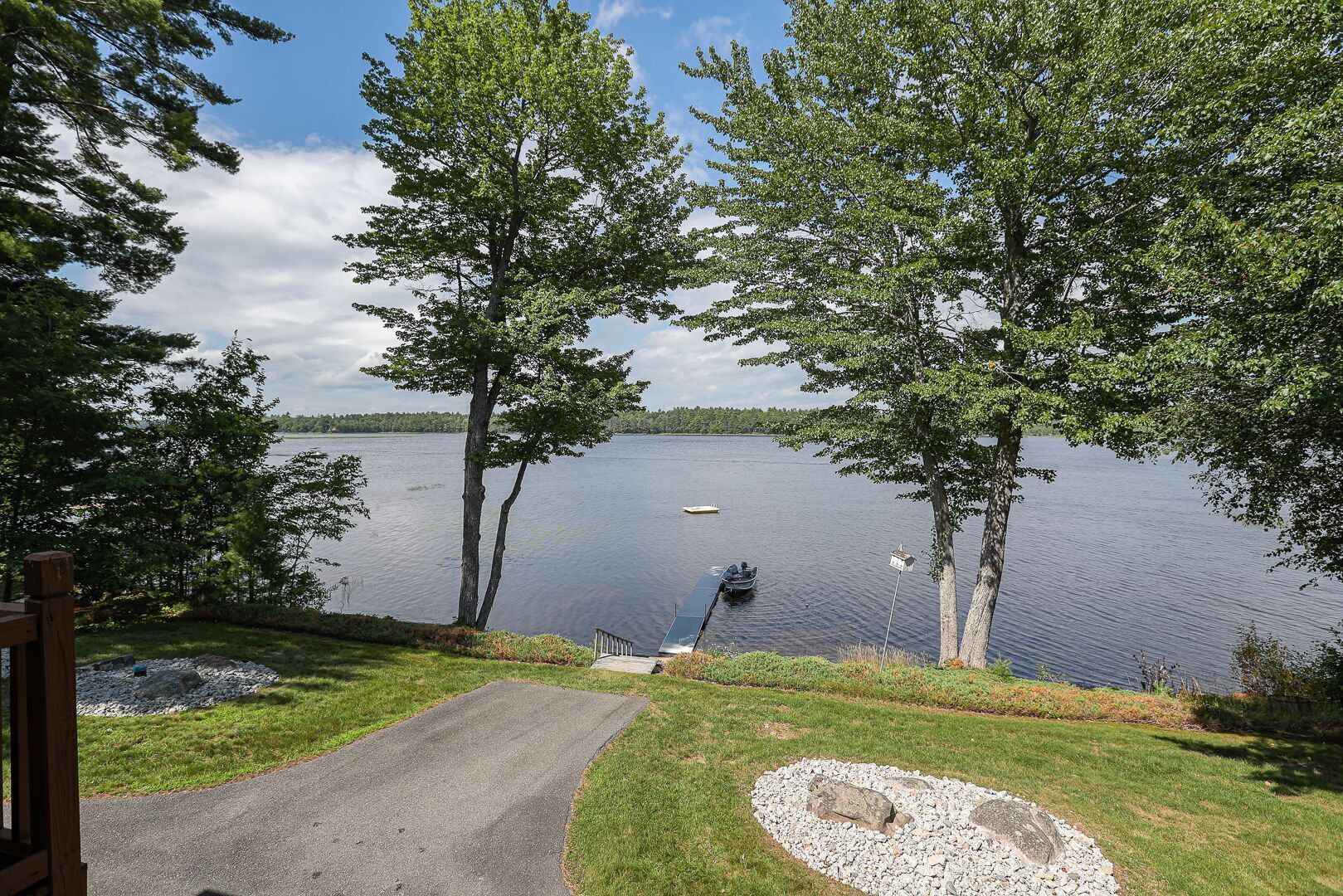 Vista sul lago con un molo per barche, un percorso lastricato e una zona verde.
