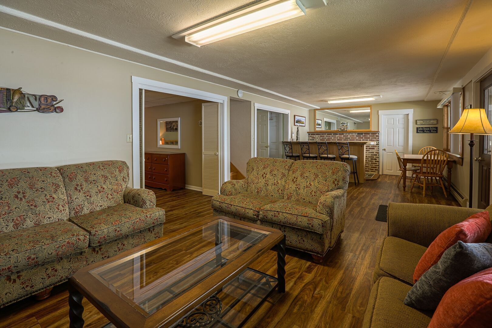 A spacious living room with a sofa set, a coffee table, and a dining area with a bar.