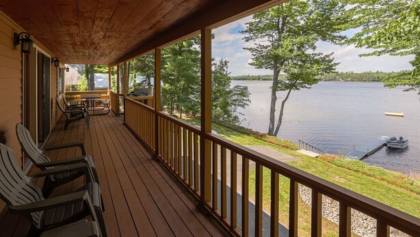 Eine Holzterrasse mit Stühlen und Tischen mit Blick auf einen See.