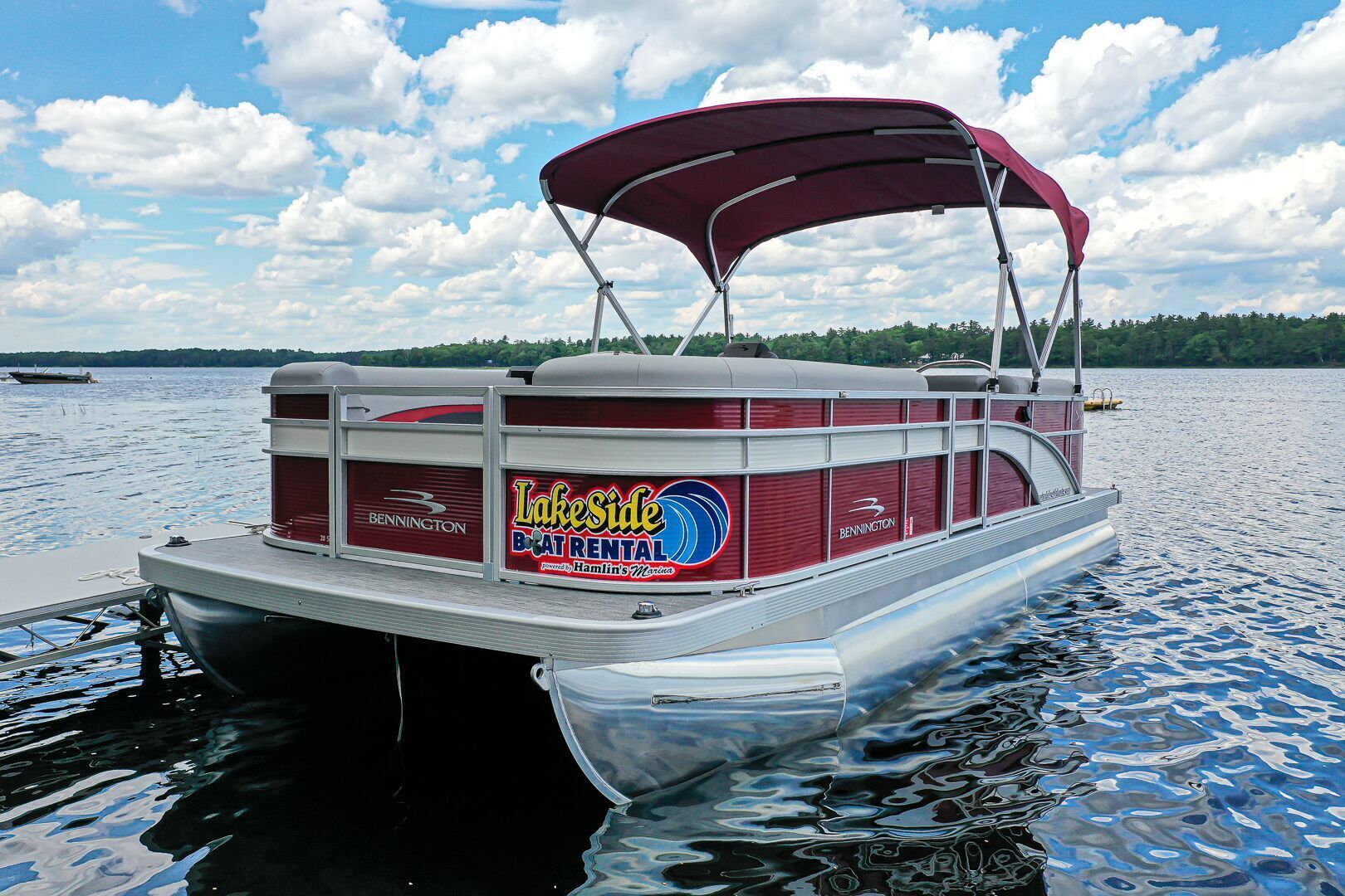 A pontoon boat with a red canopy, branded with "LakeSide Boat Rental" and "Bennington" logos, docked on calm water.