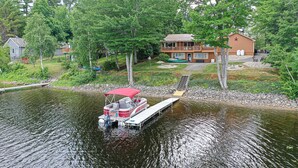Ein Seeufergrundstück mit Anlegesteg, einem Haus mit Terrasse und einem Boot.