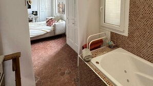 Een badkamer met een groot bad, een douchegedeelte en een betegelde vloer.