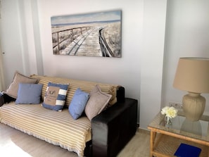 A living room with a striped sofa, a coffee table, and a lamp. - 2 bed Apt, grt Location, Shared Pool, Outdoor Area (Javea)