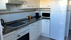 A kitchen with white cabinets, a built-in stove, a microwave, and a refrigerator. - 2 bed Apt, grt Location, Shared Pool, Outdoor Area (Javea)