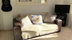 A living room with a sofa, a guitar, a painting, and a TV. - 2 bed Apt, grt Location, Shared Pool, Outdoor Area (Javea)