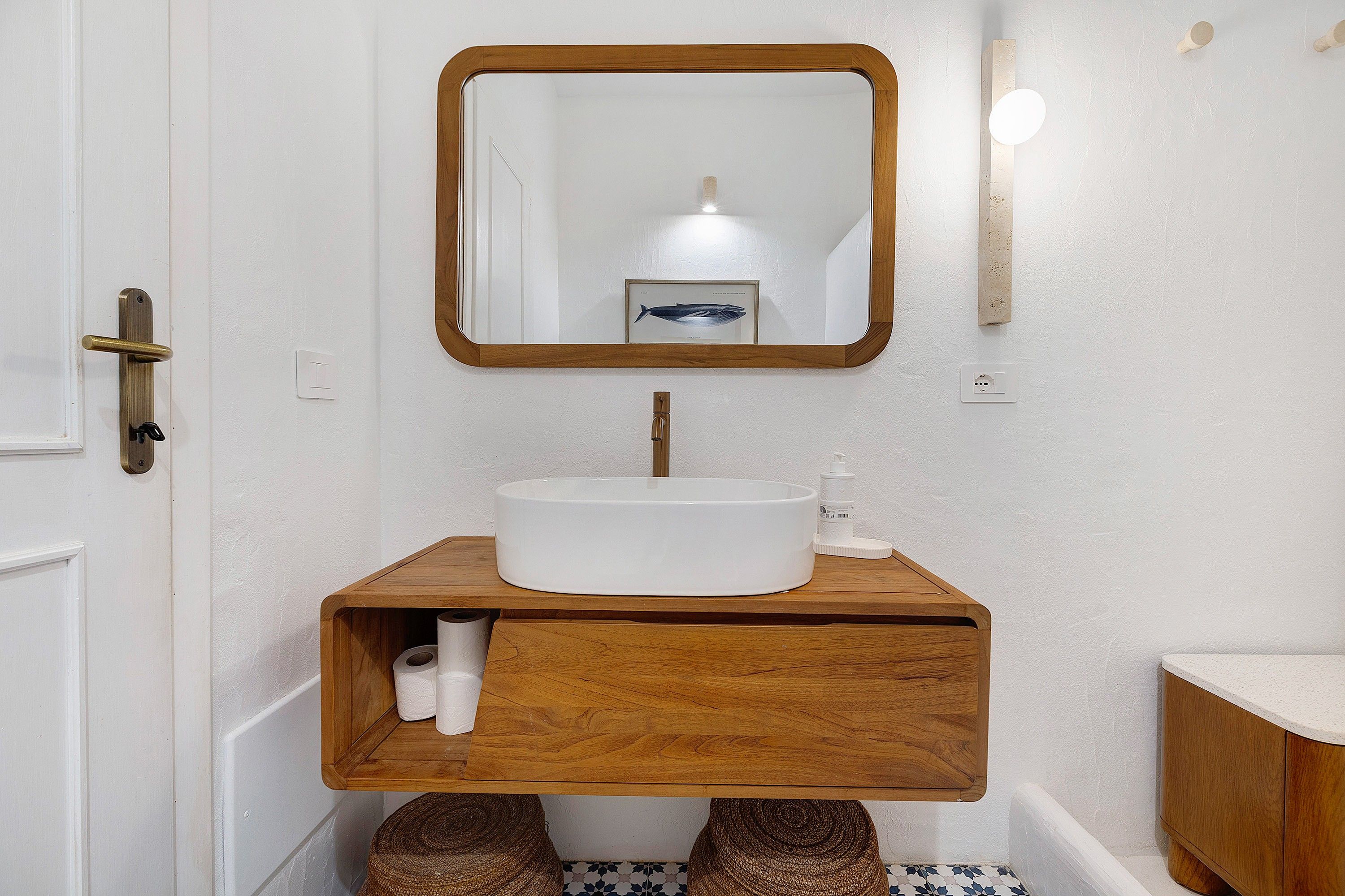 Un baño con tocador de madera, un lavamanos blanco, un espejo y un inodoro.