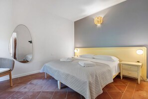 A neatly arranged bedroom with a bed, bedside tables, a chair, and a mirror. - Villa 'Sole Con Piscina Privata' with Private Pool, Wi-Fi and Air Conditioning (Punta de Su Turrione)