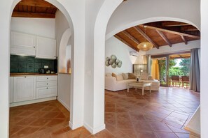 A spacious living area with a sofa and coffee table, a kitchen with white cabinets, and a dining area with outdoor seating. - Villa 'Sole Con Piscina Privata' with Private Pool, Wi-Fi and Air Conditioning (Punta de Su Turrione)