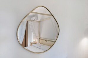 A bedroom with a bed, a nightstand, a lamp, and a wall-mounted mirror. - Villa 'Sole Con Piscina Privata' with Private Pool, Wi-Fi and Air Conditioning (Punta de Su Turrione)