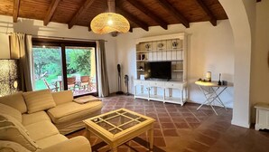 Una sala de estar con un sofá, una mesa de centro de vidrio, un televisor y un mueble.