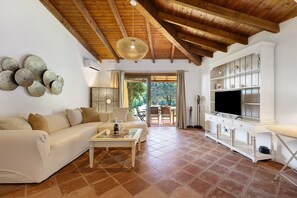 A living room with a sofa, coffee table, and TV stand. - Villa 'Sole Con Piscina Privata' with Private Pool, Wi-Fi and Air Conditioning (Punta de Su Turrione)