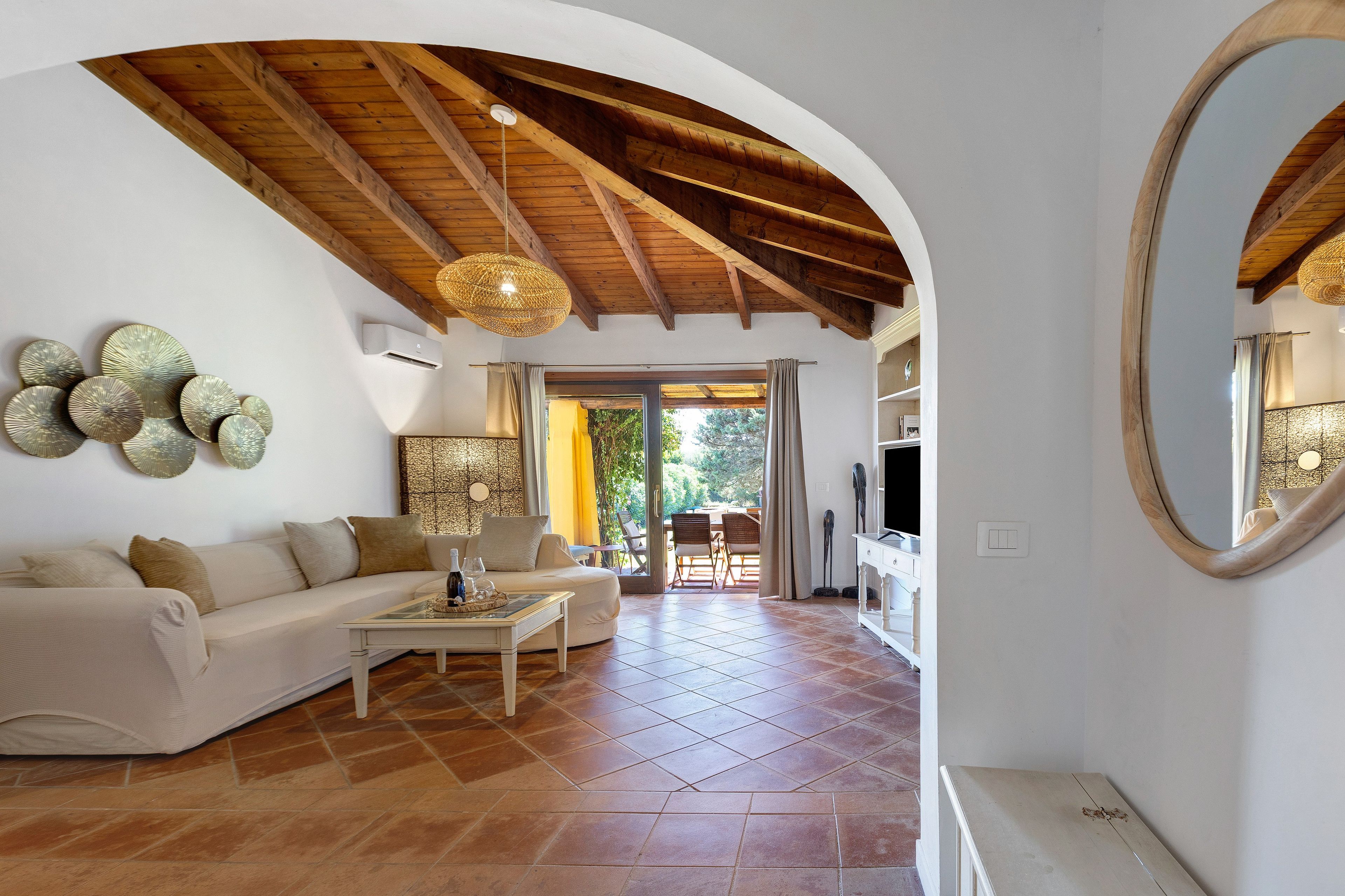 Un salon avec un plafond en bois, un canapé, une table basse et un coin repas avec des chaises.