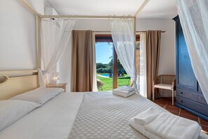 A bedroom with a bed, a nightstand, a chair, and a view of a swimming pool. - Villa 'Sole Con Piscina Privata' with Private Pool, Wi-Fi and Air Conditioning (Punta de Su Turrione)