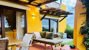 Un patio con un sofá, sillas, una mesa y una mesita con un jarrón.