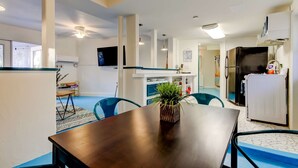 Eine moderne Küche mit weißen Schränken, einem schwarzen Kühlschrank und einem Essbereich mit Holztisch und Stühlen.