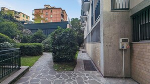 A stone pathway leading to a building with a metal railing on one side and a small garden area with bushes. - Stica Loft Apartment (Milano)