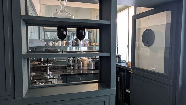 A kitchen with dark cabinetry, a countertop with kitchenware, and a window with a view of the outside. - Stica Loft Apartment (Milano)