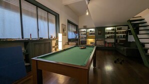 A pool table in a room with a bookshelf, a staircase, and a radiator. - Stica Loft Apartment (Milano)