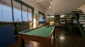 A pool table in a room with a bookshelf, a staircase, and a radiator. - Stica Loft Apartment (Milano)
