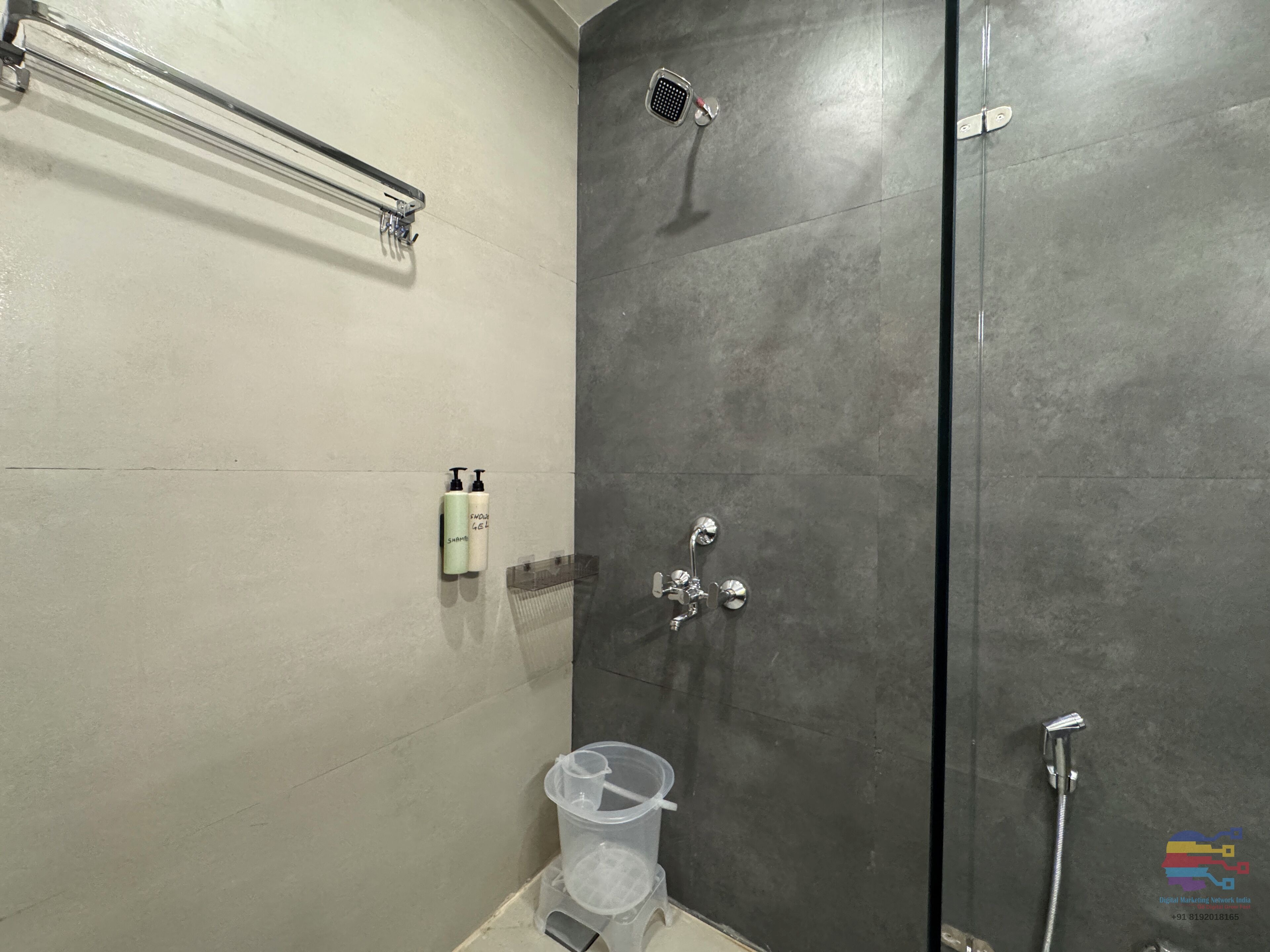 A modern bathroom with a shower, a towel rack, and two bottles of shampoo and conditioner.