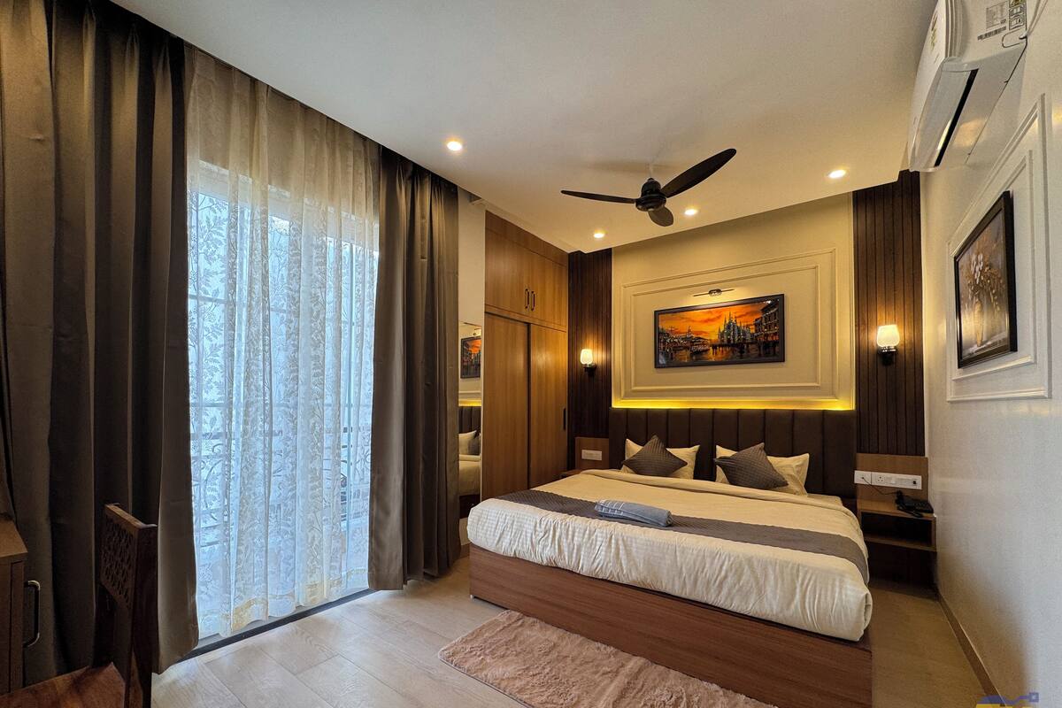 A modern hotel room with a large bed, a ceiling fan, and a painting on the wall.