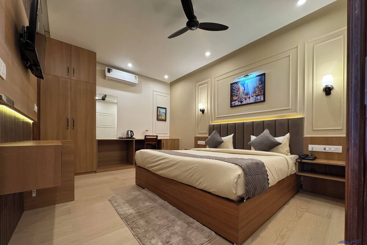 A modern bedroom with a large bed, a desk, a wardrobe, and a ceiling fan.