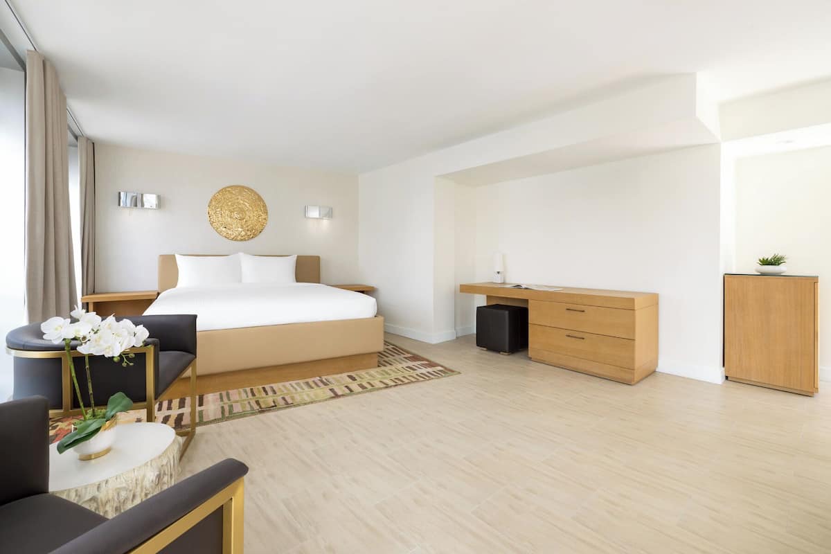 Una habitación de hotel moderna con una cama grande, mesitas de noche, un escritorio y una silla.