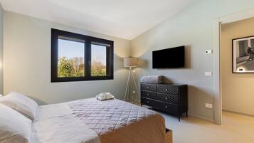 Quarto com uma cama, cômoda, abajur, televisão e janela.