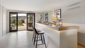 Eine moderne Küche mit Bar, einer Schiebetür zu einer Terrasse und Blick ins Freie.