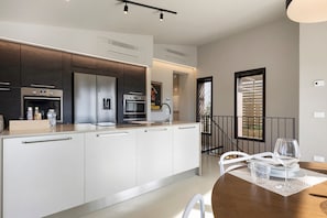 A modern kitchen with built-in appliances, a dining area with a table and chairs, and a staircase leading to another level.