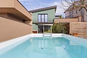 Une piscine offrant une vue dégagée sur une maison moderne en arrière-plan.