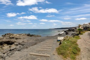 A coastal path with steps leading to a rocky beach, a clear sky, and distant wind turbines. - Vacation Home 'Casa Del Pescador 2' with Private Terrace, Balcony and Wi-Fi (Santa Cruz de Tenerife)