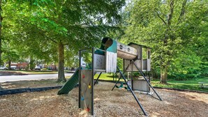 Un parque infantil con una estructura para escalar, un tobogán y columpios.