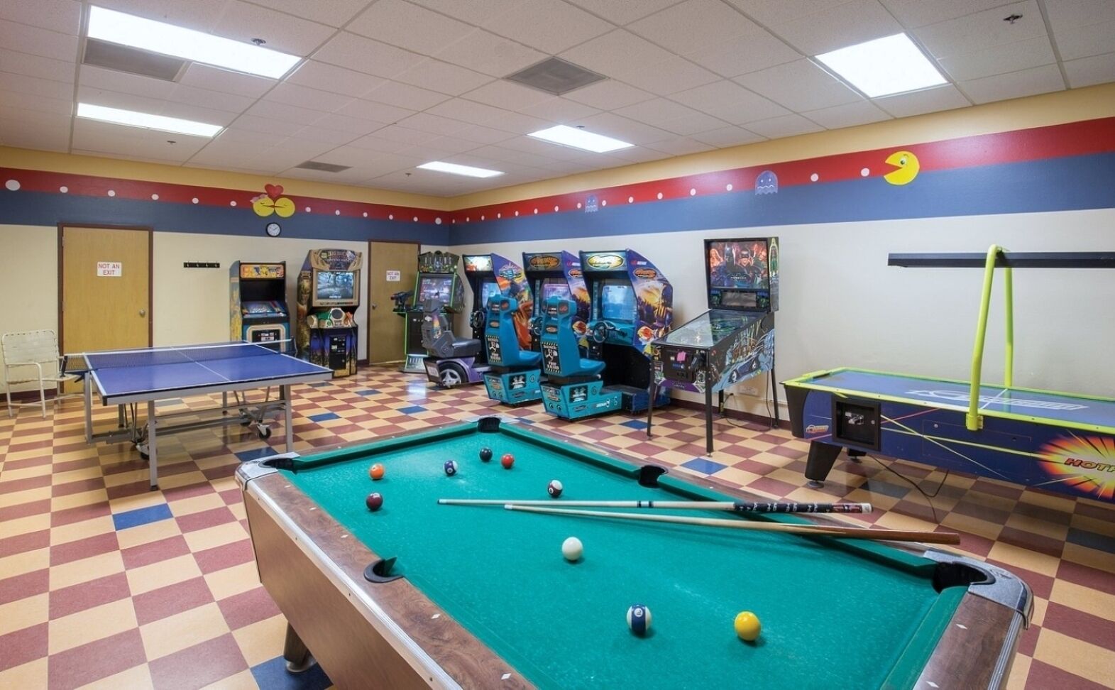 A recreational room with a pool table, billiards, and various arcade games.