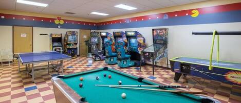 A recreational room with a pool table, billiards, and various arcade games.