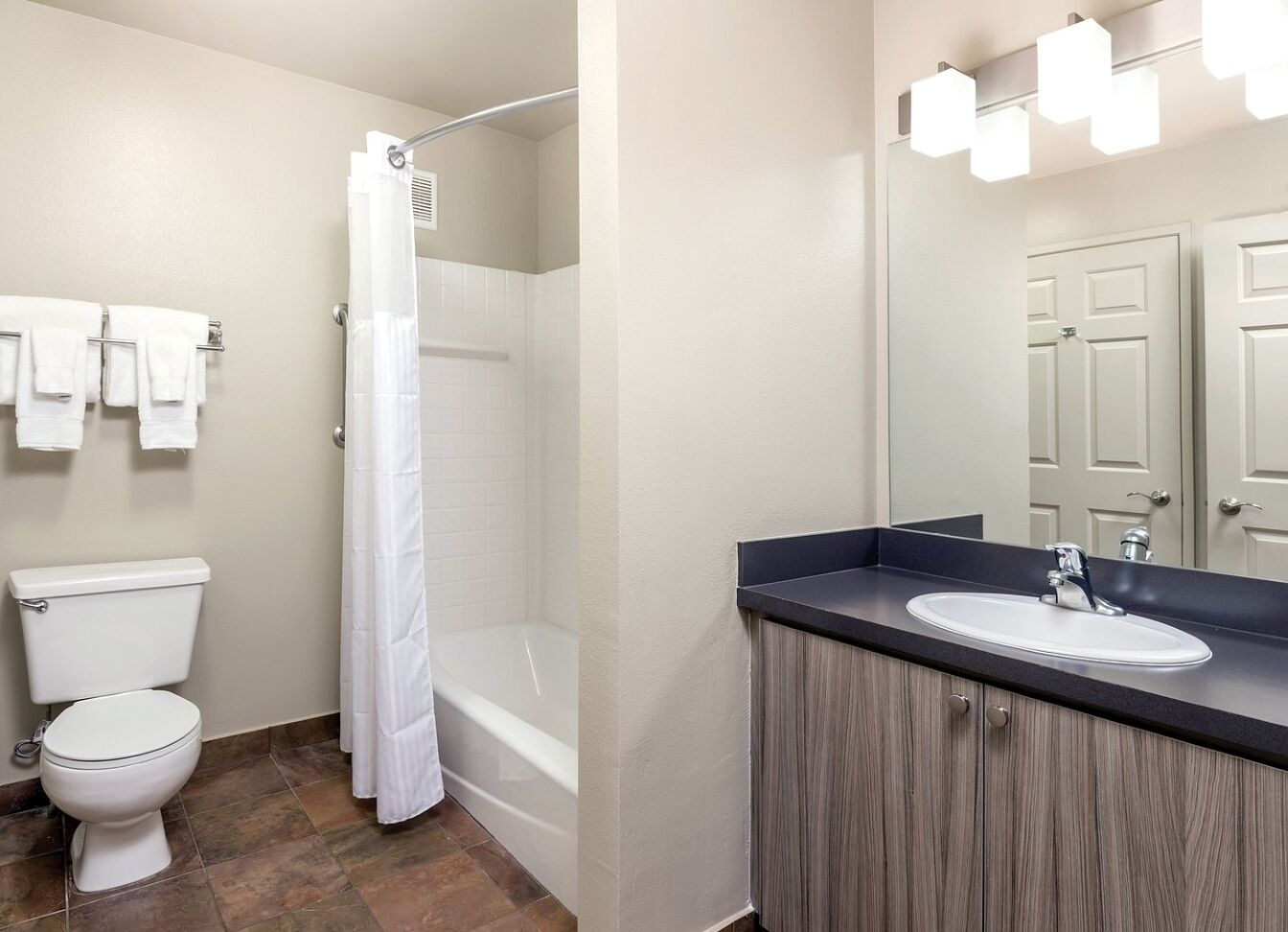 A bathroom with a toilet, shower, and sink.