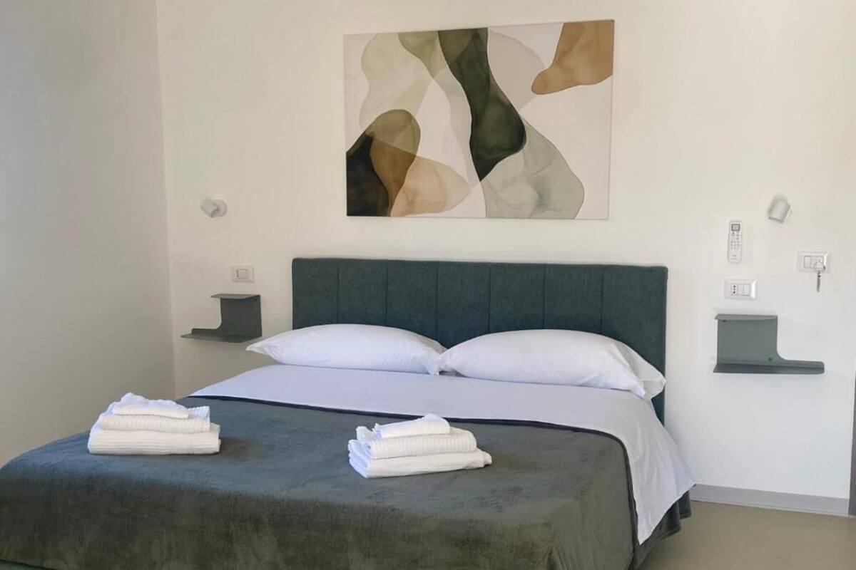 A neatly made bed with a grey headboard, white pillows, and folded towels on the bed.