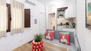 A compact living space with a kitchenette, a dining area with a wooden table, and a sofa with decorative pillows. - Jungle (Bass 3) (Granada)