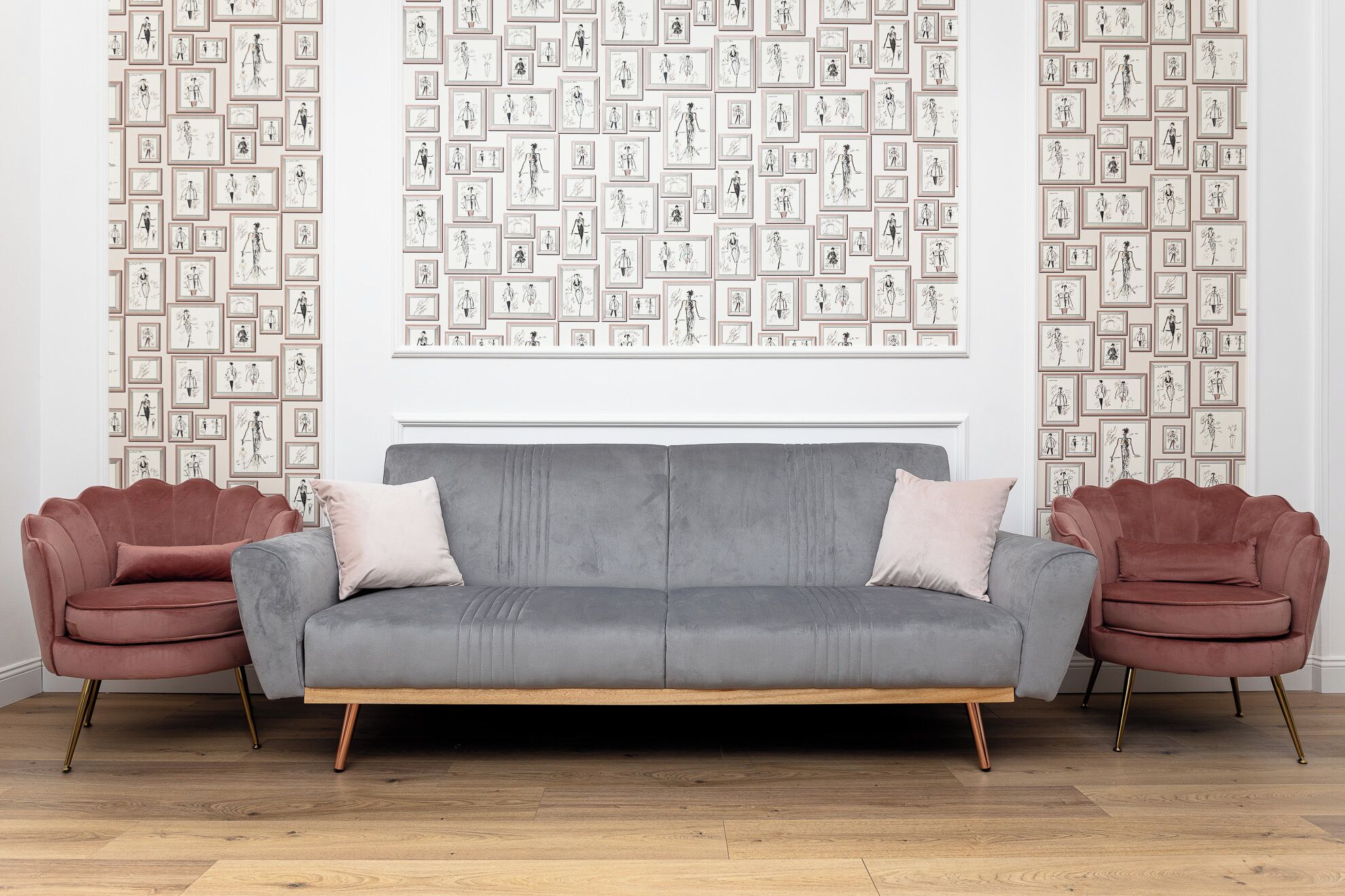 A modern living room with a grey sofa, two pink armchairs, and a wall decorated with framed sketches.