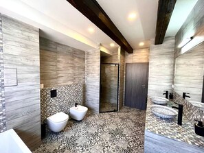 Un baño moderno con un bidé, ducha y tocador con un espejo grande.